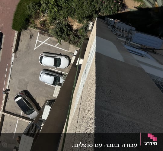 מבט מלמעלה על חניה ומדרכה ליד בניין גבוה